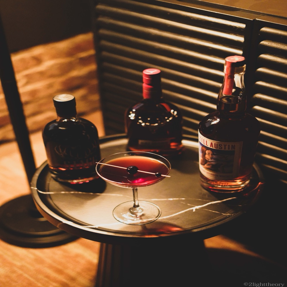 Bottles and a drink on a table by the blinds